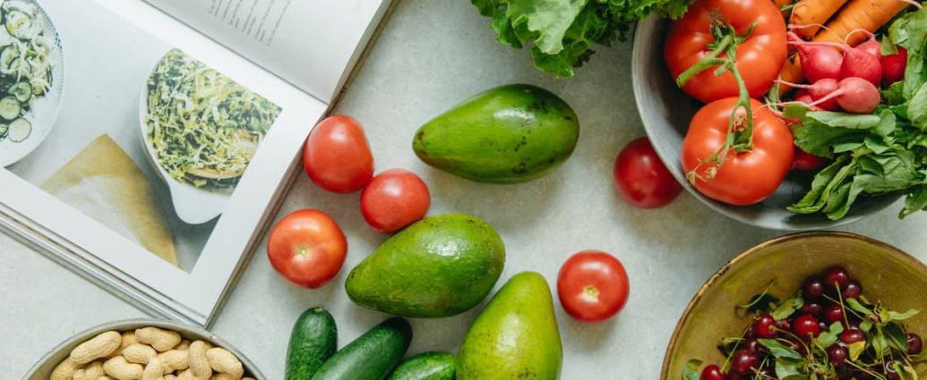 An appetizing display of fresh fruits and vegetables with a cookbook, perfect for healthy recipes.