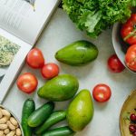 An appetizing display of fresh fruits and vegetables with a cookbook, perfect for healthy recipes.