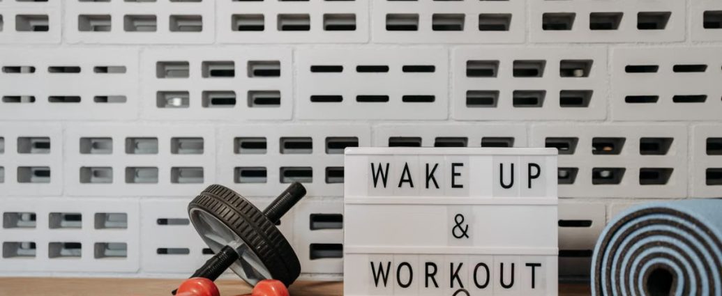 Fitness gear and motivational sign in home gym setup against a brick wall.