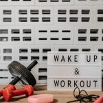 Fitness gear and motivational sign in home gym setup against a brick wall.